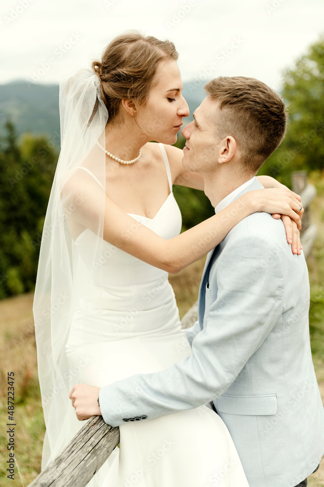 Beautiful newlyweds hug and smile being in nature. Portrait of the bride and groom in a lace dress. Wedding day of a happy couple of newlyweds. couple in the mountains