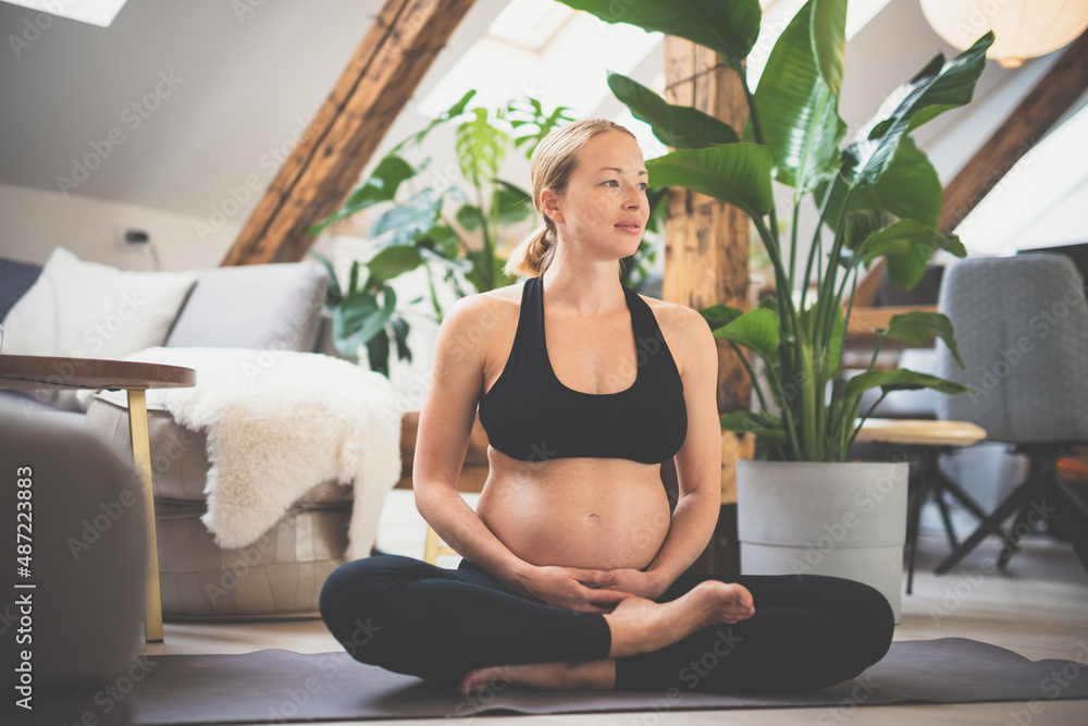 Young beautiful pregnant woman training yoga, caressing her belly. Young  happy expectant relaxing, thinking about her baby and enjoying her future  life. Motherhood, pregnancy, yoga concept. Photos