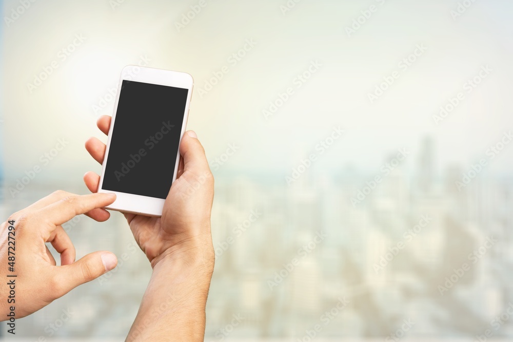Human hand holding phone with blank screen and cityscape blur background