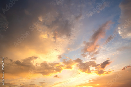 Dramatic sunset landscape with puffy clouds lit by orange setting sun and blue sky © bilanol
