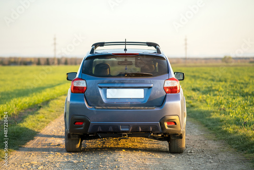 Landscape with blue off road car on gravel road. Traveling by auto, adventure in wildlife, expedition or extreme travel on a SUV automobile. Offroad 4x4 vehicle in field at sunrise