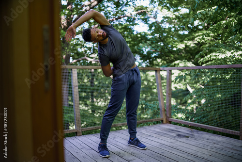 Young man doing exercise outdoors on terrace of tree house, weekend away and digital detox concept. © Halfpoint