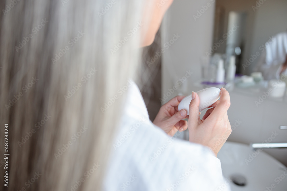 Close-up photo of soft woman hands holding cosmetic jar