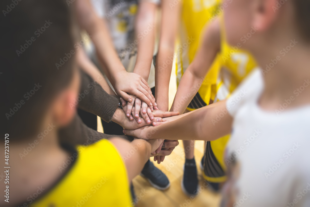 Team of kids children basketball players stacking hands in the court, sports team together holding hands getting ready for the game, playing indoor basketball, team talk with coach, close up of hands Team of kids children basketball players stacking hands in the court, sports team together holding hands getting ready for the game, playing indoor basketball, team talk with coach, close up of hands