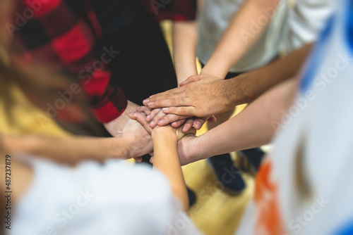 Team of kids children basketball players stacking hands in the court, sports team together holding hands getting ready for the game, playing indoor basketball, team talk with coach, close up of hands © tsuguliev