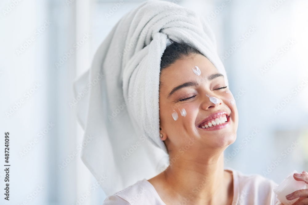 Not a wrinkle in sight. Shot of a beautiful young woman applying moisturizer to her skin in the bathroom at home. Not a wrinkle in sight. Shot of a beautiful young woman applying moisturizer to her skin in the bathroom at home.