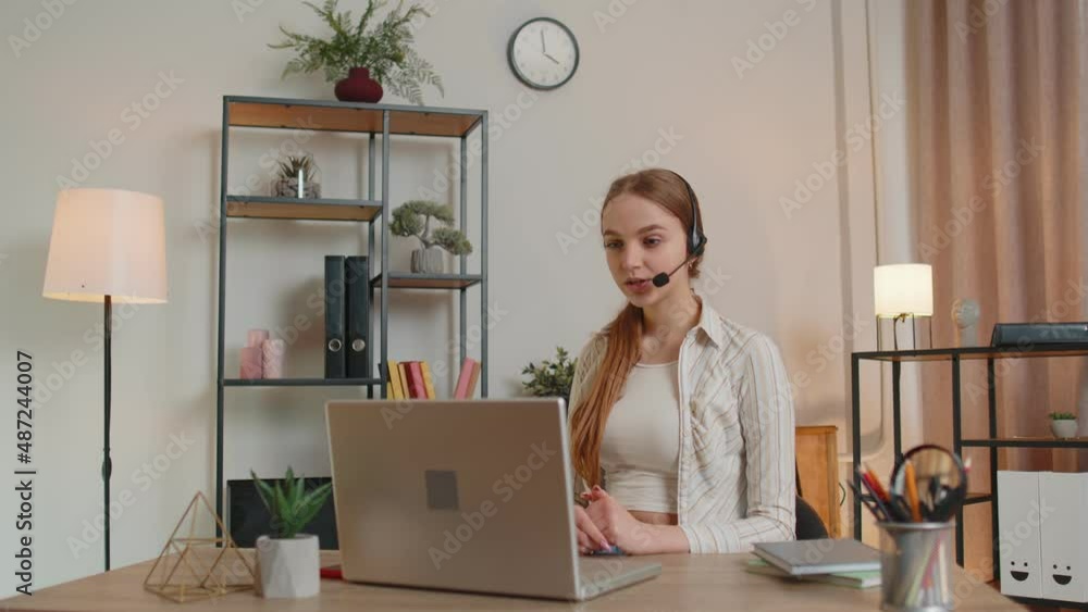 Young woman with headset using laptop pc, talking, working customer support service operator at home office, in headphones with microphone in living room. Coronavirus quarantine distance isolation Young woman with headset using laptop pc, talking, working customer support service operator at home office, in headphones with microphone in living room. Coronavirus quarantine distance isolation