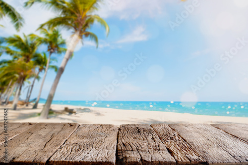 Fototapeta Naklejka Na Ścianę i Meble -  Top of wood table with seascape and palm tree, blur bokeh light of calm sea and sky at tropical beach background. Empty ready for your product display montage. summer vacation background concept.