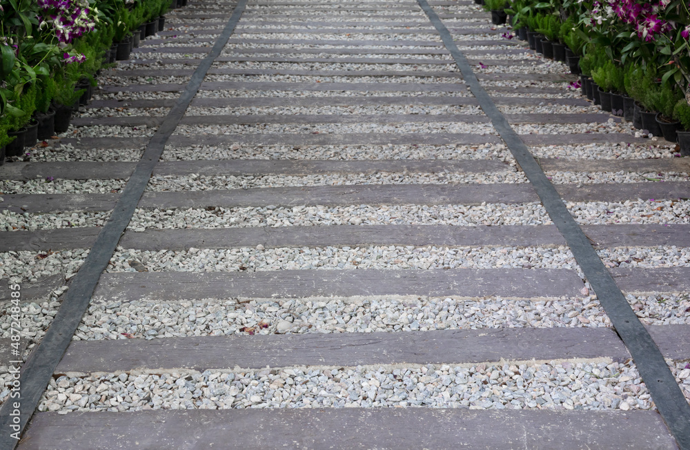 The textured background of pebbles and planks for a garden footpath with gray horizontal stripes. The textured background of pebbles and planks for a garden footpath with gray horizontal stripes.