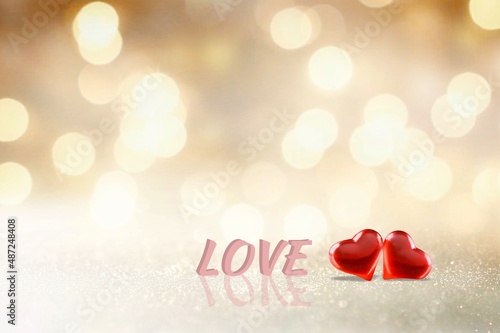 Two red handmade hearts and word love on bright glitter lights bokeh background