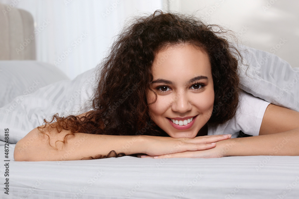 Happy beautiful African American woman lying in bed at home Happy beautiful African American woman lying in bed at home