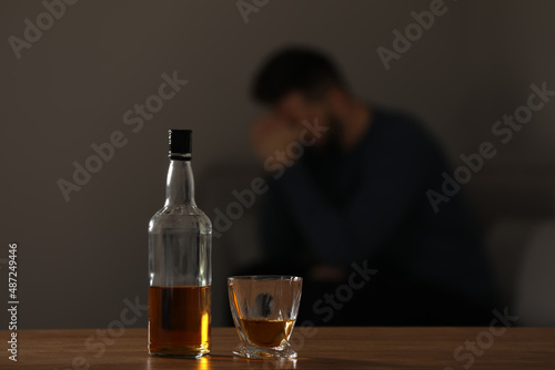 Addicted man at home  focus on table with alcoholic drink. Space for text