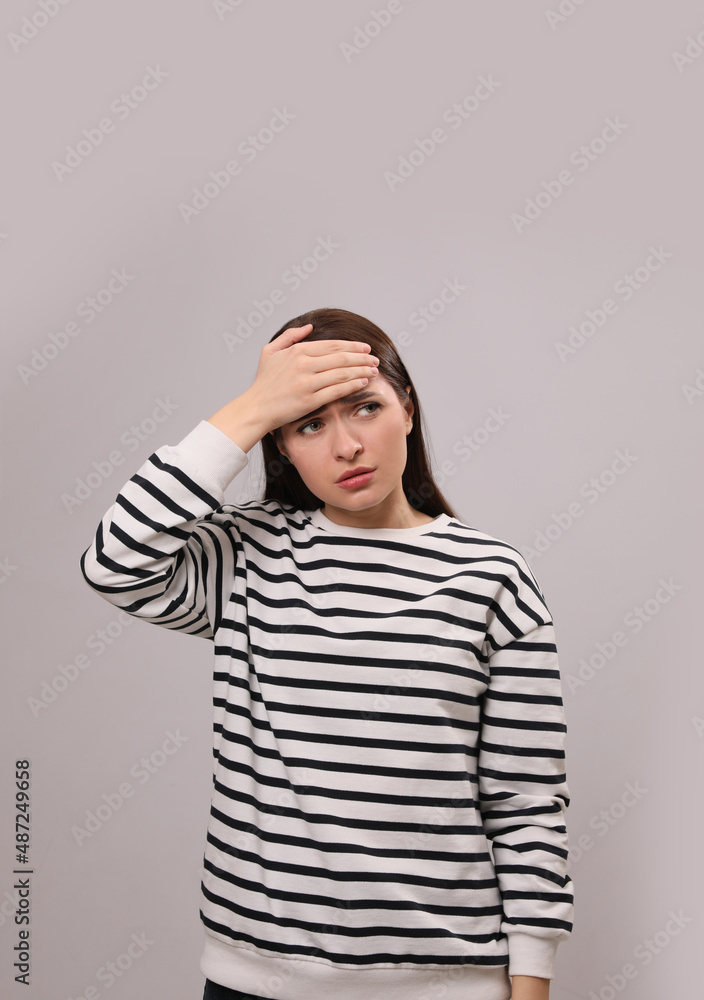 Woman suffering from headache on light grey background. Cold symptoms Woman suffering from headache on light grey background. Cold symptoms