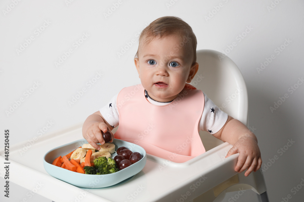 Cute little baby wearing bib while eating on white background Cute little baby wearing bib while eating on white background