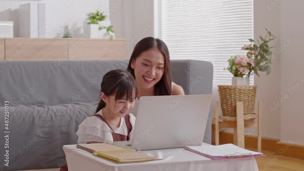 Asian young mother and her daughter have video call conference with family having fun together.Happiness Mom and little girl looking at mobile phone and waving hand with video chat to grandmother Asian young mother and her daughter have video call conference with family having fun together.Happiness Mom and little girl looking at mobile phone and waving hand with video chat to grandmother