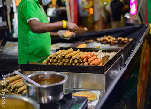 Street foods at a night food festival held in Galle Fort, Sri Lanka. chef making hot dogs with sausages close up.