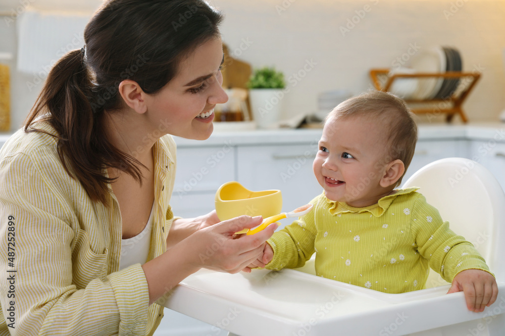 Mother feeding her cute little baby in kitchen Mother feeding her cute little baby in kitchen