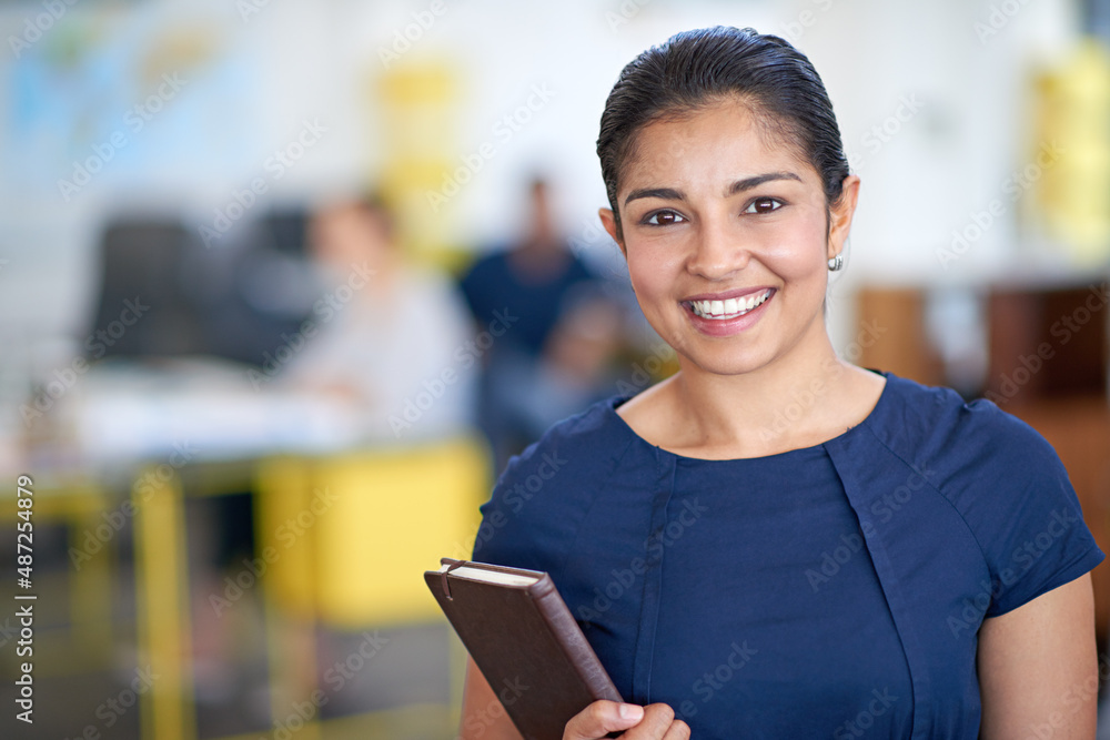 Shes a positive professional. Portrait of an attractive young businesswoman holding her journal while standing in an office. Shes a positive professional. Portrait of an attractive young businesswoman holding her journal while standing in an office.