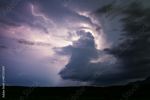 Lightning illuminates a supercell thunderstorm cloud in the night sky