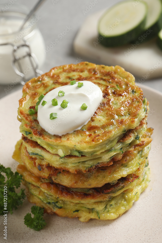 Delicious zucchini fritters with sour cream on plate Delicious zucchini fritters with sour cream on plate