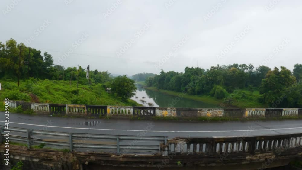 View of road with clear water of the Ambika River besides road as seen from a moving vehicle at Dang district in Gujarat, India. Beautiful View of the roads of Saputara. View of road with clear water of the Ambika River besides road as seen from a moving vehicle at Dang district in Gujarat, India. Beautiful View of the roads of Saputara.