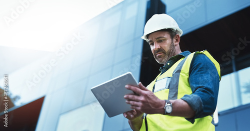 This software help me to keep track of everything. Shot of a engineer using a digital tablet on a construction site. photo
