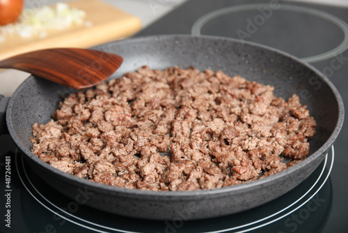 Frying minced meat in pan on induction stove, closeup