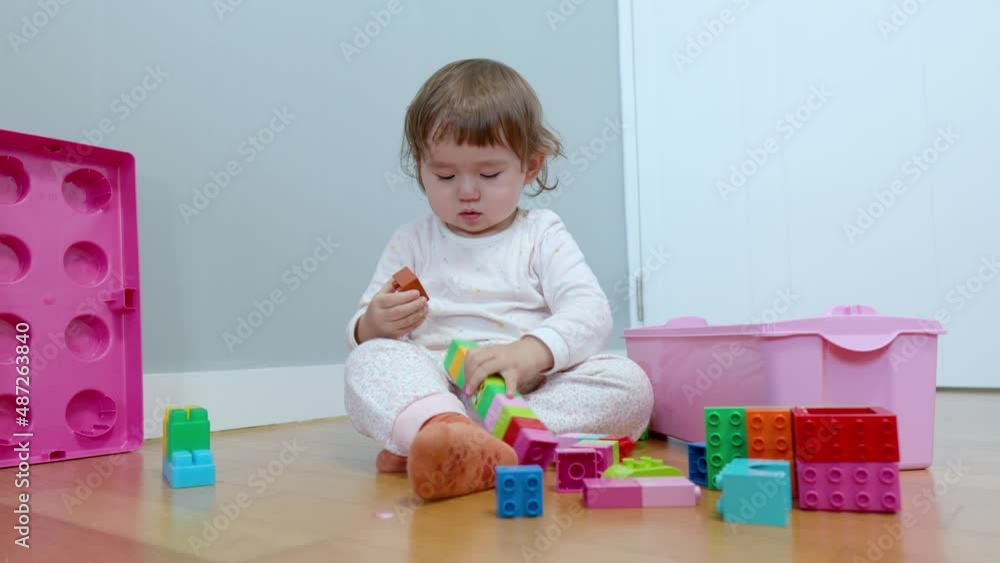 Adorable two years old toddler girl having fun making tower from colorful bricks Adorable two years old toddler girl having fun making tower from colorful bricks