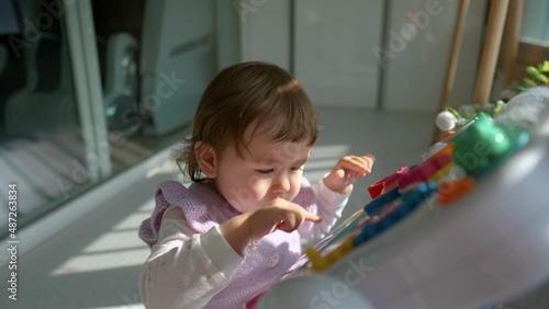 Little toddler baby girl pressing buttons with fingers on educational table toy - kids early development concept photo