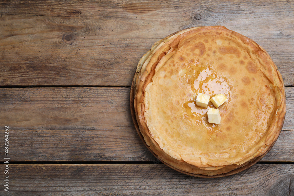 Stack of delicious crepes with melting butter on wooden table, top view. Space for text Stack of delicious crepes with melting butter on wooden table, top view. Space for text