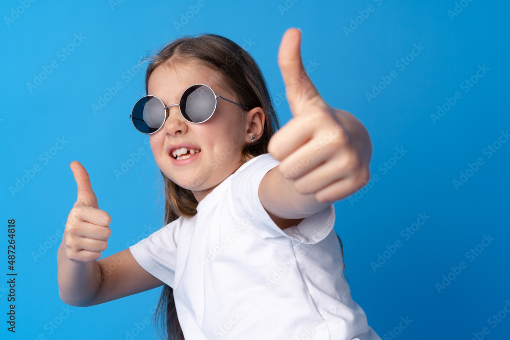 Portrait of teen girl making thumb up gesture on blue background Portrait of teen girl making thumb up gesture on blue background