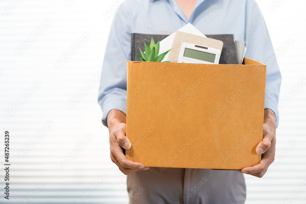 Resignation Concept The male standing and using his hands lifting a box of his stuff Resignation Concept The male standing and using his hands lifting a box of his stuff