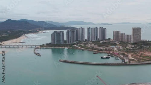 Hotel resort complex on artificial island in Hainan island, China with beach and mountain ridge in background in early morning. photo