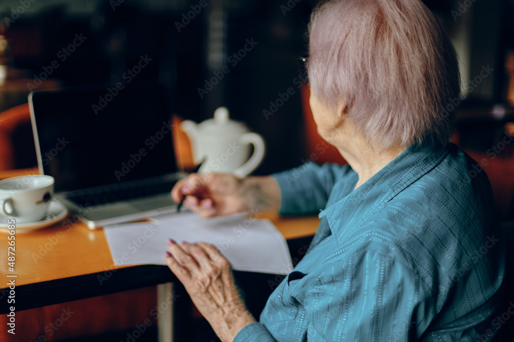 Happy senior woman documents work sheet of paper and pen Freelancer works unaltered Happy senior woman documents work sheet of paper and pen Freelancer works unaltered