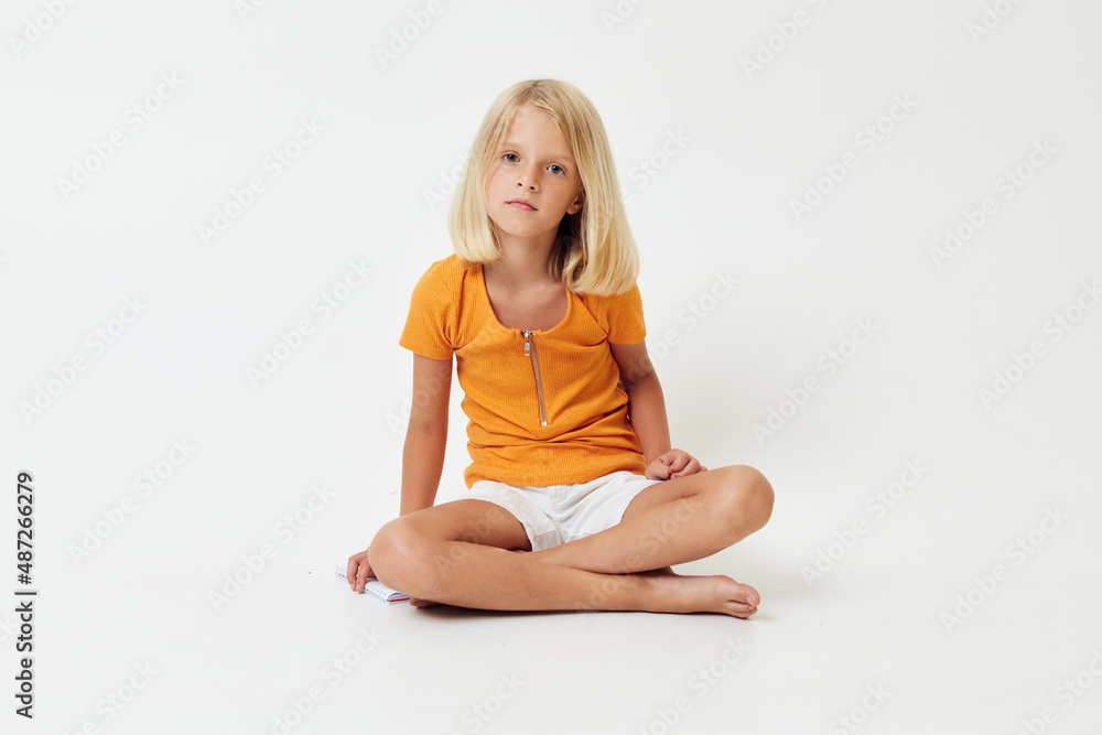 little girl with blond hair gesturing with her hands while sitting on the floor little girl with blond hair gesturing with her hands while sitting on the floor