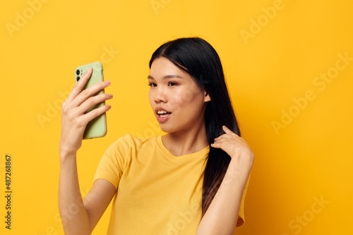 pretty brunette in a yellow t-shirt looking at the phone posing isolated background unaltered