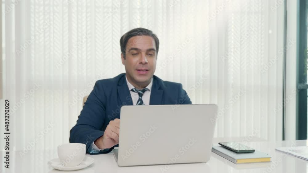 Business man sitting using laptop computer videoconferencing with colleagues on desk, happy man participating talking online video conference call virtual meeting remote working online in office Business man sitting using laptop computer videoconferencing with colleagues on desk, happy man participating talking online video conference call virtual meeting remote working online in office
