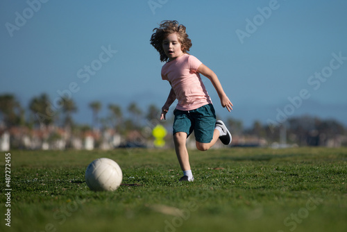 Soccer kids, child boy play football outdoor. Young boy with soccer ball doing kick. Football soccer players in motion. Cute boy in sport action.
