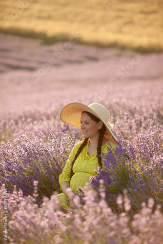 pregnant Woman in lavender flowers field at sunset in yellow dress.