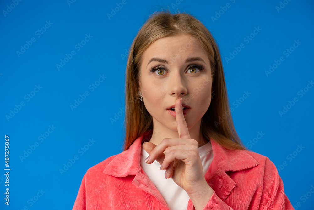Young pretty woman showing silence gesture over blue background - obrazy, fototapety, plakaty 