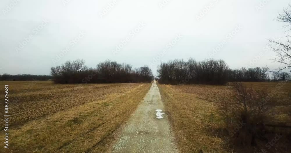 Drone fly above lonely remote desolated road in countryside driving through plowed agricultural field Drone fly above lonely remote desolated road in countryside driving through plowed agricultural field