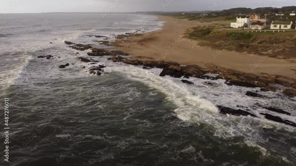 Waves crashing on jagged and rocky coast on cloudy day, La Pedrera beach in Uruguay. Aerial drone view Waves crashing on jagged and rocky coast on cloudy day, La Pedrera beach in Uruguay. Aerial drone view