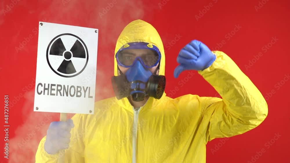 Man in Protective Chemical Suit, Mask and Banner in Hands. Chernobyl Shows Thumb Down. Smoke Around Man. Protection Concept, Radioactive Hazard Concept. Red background, Isolate, Studio Footage, 4k Man in Protective Chemical Suit, Mask and Banner in Hands. Chernobyl Shows Thumb Down. Smoke Around Man. Protection Concept, Radioactive Hazard Concept. Red background, Isolate, Studio Footage, 4k