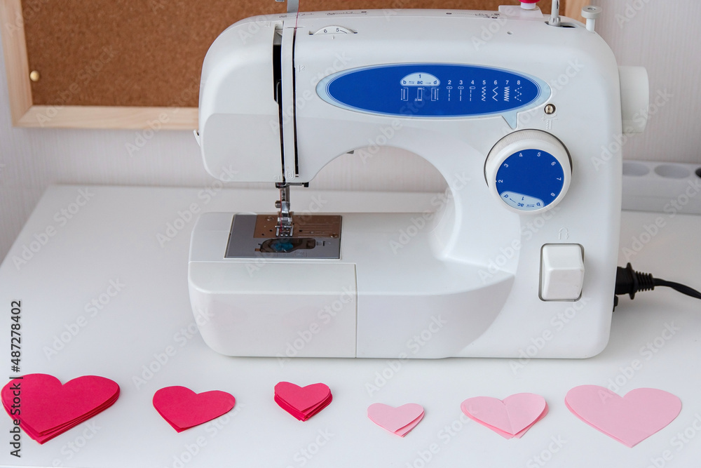 Sewing machine and paper hearts. The process of making a garland. Concept to sew with love, Valentines Day.