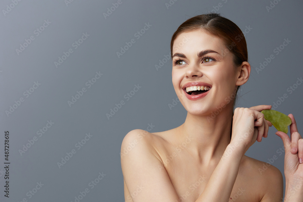 portrait woman scraper gua sha facial care home facial massage Gray background portrait woman scraper gua sha facial care home facial massage Gray background