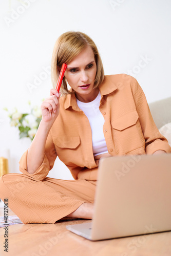 Skillful freelancer blogging at home. Female working on laptop on the floor