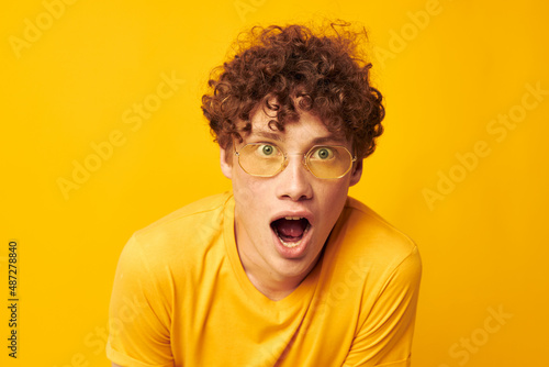 cute red-haired guy wearing stylish glasses yellow t-shirt posing yellow background unaltered © Tatiana