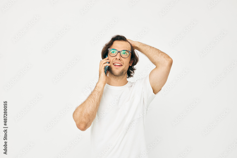 Attractive man in a white T-shirt communication by phone light background