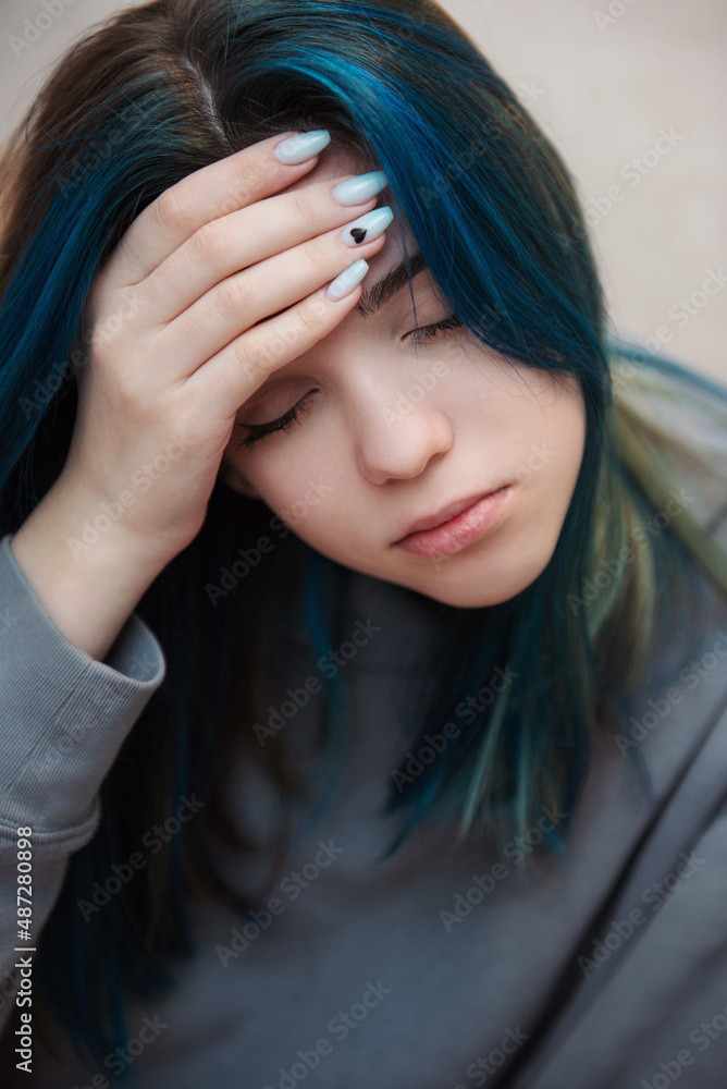 A teenage girl with blue hair is sad and depressed A teenage girl with blue hair is sad and depressed