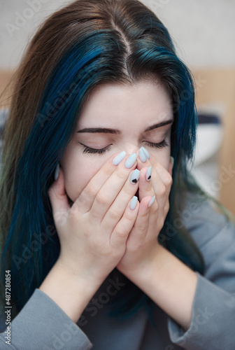 A teenage girl with blue hair is sad and depressed